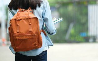 estudante de costas de mochila segurando cadernos.